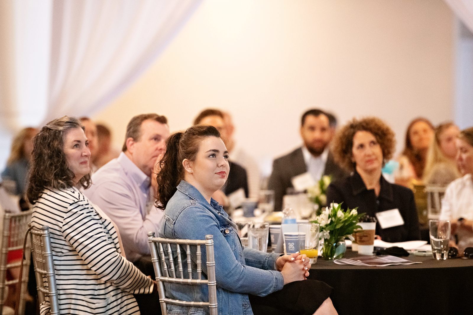 Nonprofit leaders seated at round tables listening during a Mi Gulf Coast luncheon