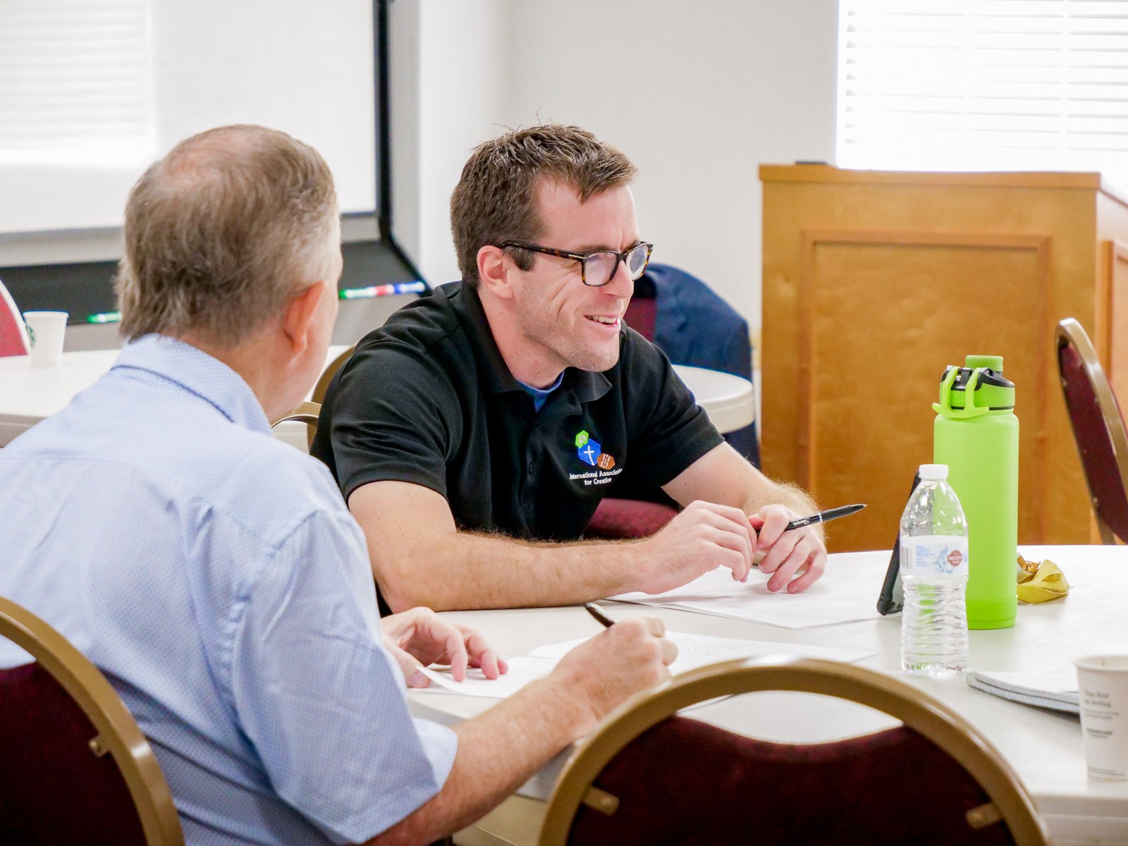 A Mi Gulf Coast coach and a nonprofit leader talking one-on-one across a workshop table